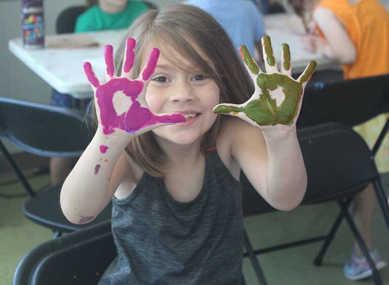 Student in art class with paint on hands