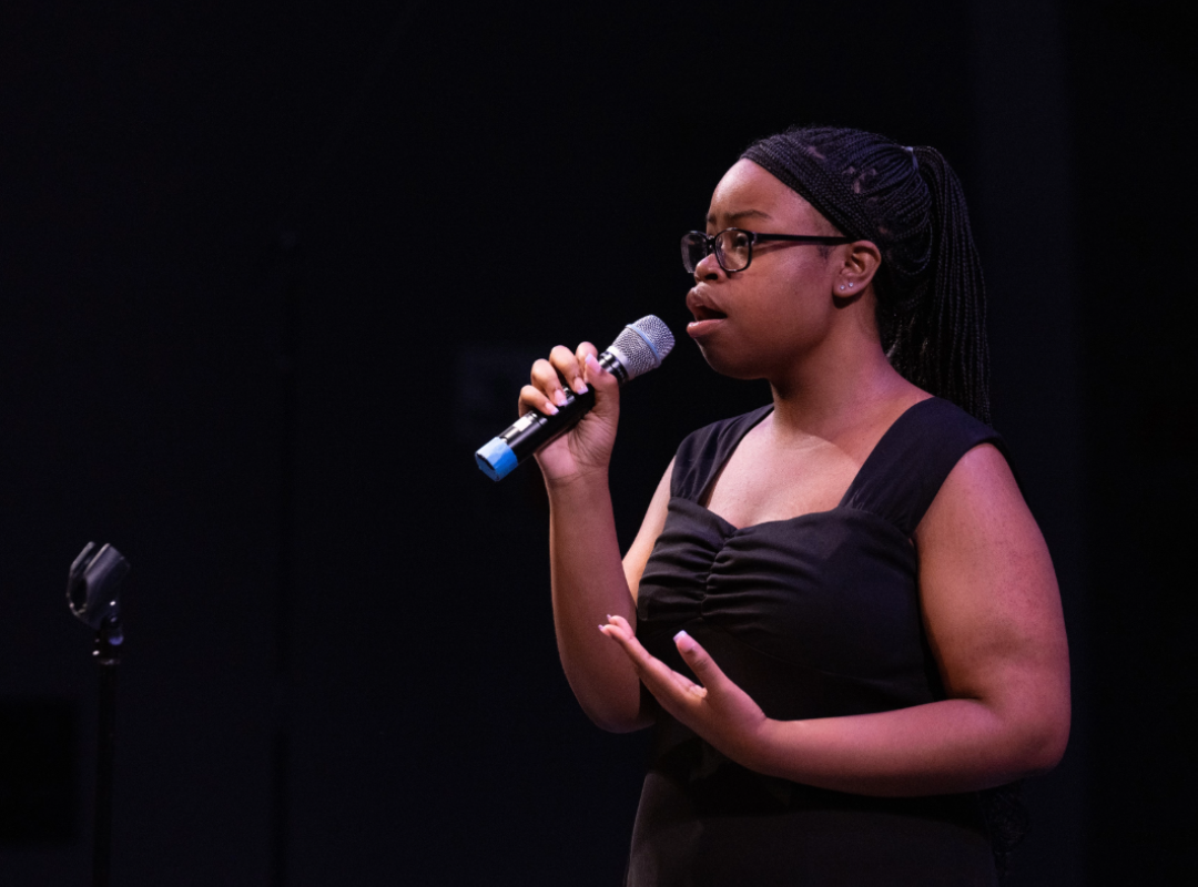 Vocal student holding microphone and performing on stage